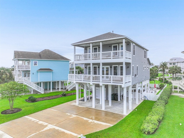 rear view of house featuring concrete driveway, a balcony, roof with shingles, stairs, and a carport