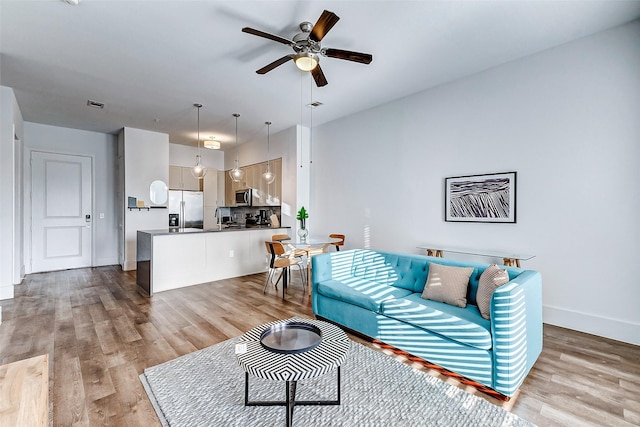 living room with ceiling fan and light hardwood / wood-style flooring