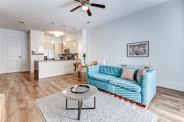 living room featuring ceiling fan and light hardwood / wood-style floors