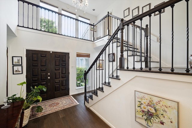 foyer featuring hardwood / wood-style floors, a towering ceiling, an inviting chandelier, and a wealth of natural light