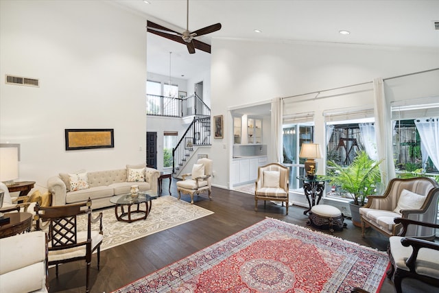 living room featuring ceiling fan with notable chandelier, high vaulted ceiling, and dark wood-type flooring