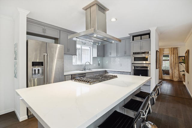 kitchen with a center island, a kitchen breakfast bar, dark hardwood / wood-style floors, island exhaust hood, and stainless steel appliances