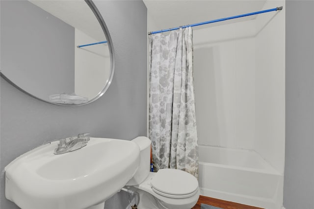 full bathroom with wood-type flooring, toilet, shower / bathtub combination with curtain, and sink