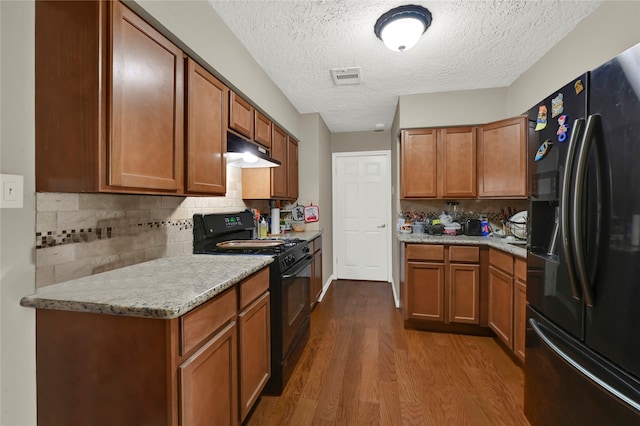 kitchen with decorative backsplash, black appliances, a textured ceiling, and hardwood / wood-style flooring