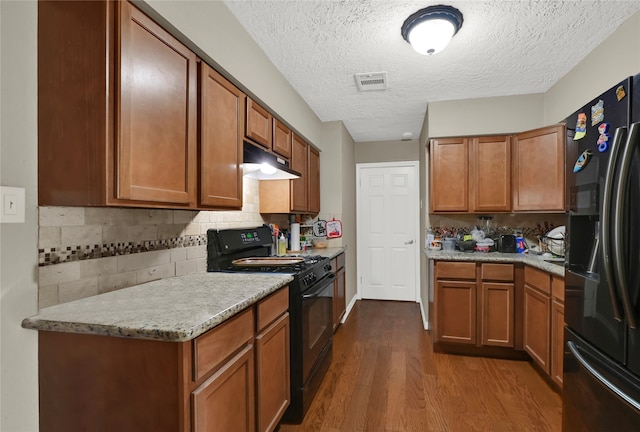 kitchen featuring black appliances, dark hardwood / wood-style floors, decorative backsplash, and a textured ceiling