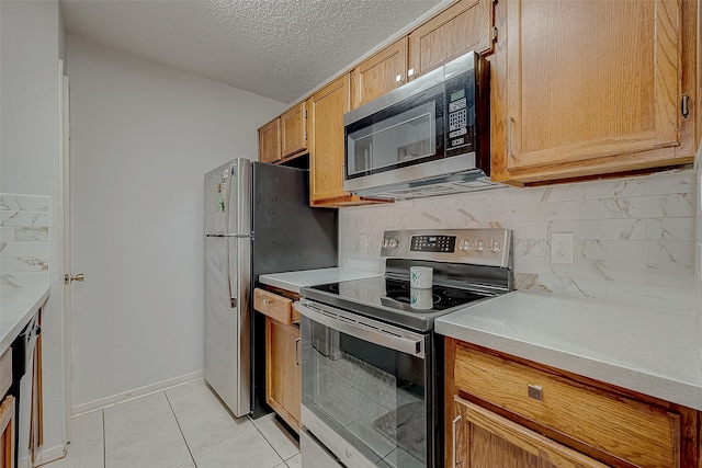 kitchen with decorative backsplash, light tile patterned floors, stainless steel appliances, and a textured ceiling