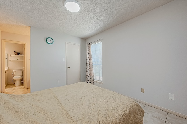 tiled bedroom featuring a textured ceiling and connected bathroom