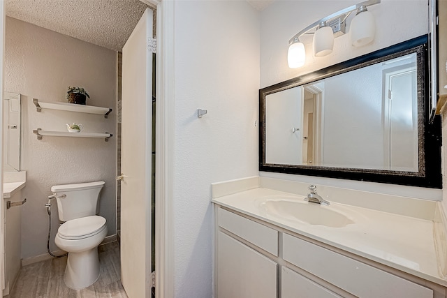 bathroom with hardwood / wood-style floors, vanity, toilet, and a textured ceiling