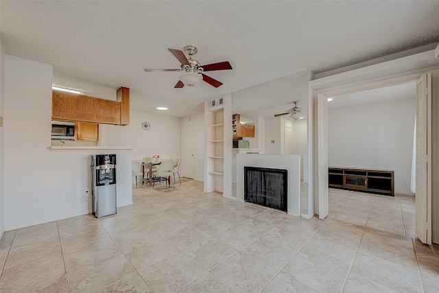 tiled living room featuring a textured ceiling, built in features, and ceiling fan