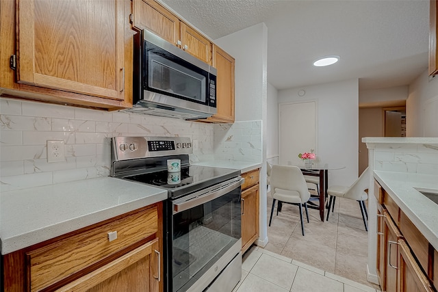 kitchen featuring decorative backsplash, stainless steel appliances, and light tile patterned flooring