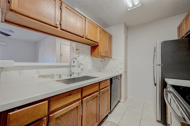 kitchen with sink, a textured ceiling, decorative backsplash, light tile patterned floors, and appliances with stainless steel finishes