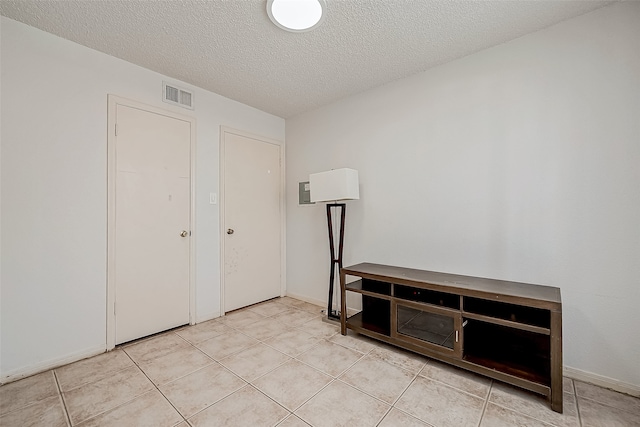 unfurnished bedroom with a textured ceiling and light tile patterned flooring