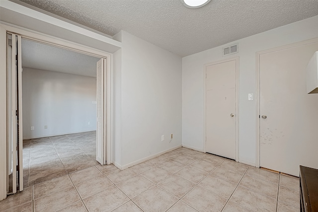 empty room with light tile patterned floors and a textured ceiling