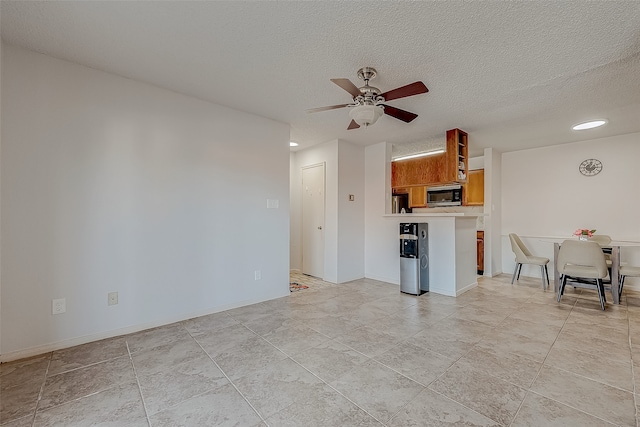 unfurnished living room with a textured ceiling, ceiling fan, and light tile patterned flooring