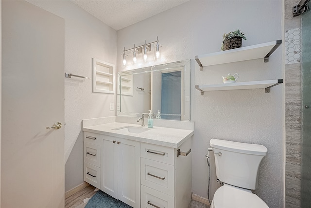 bathroom with hardwood / wood-style floors, vanity, a textured ceiling, and toilet