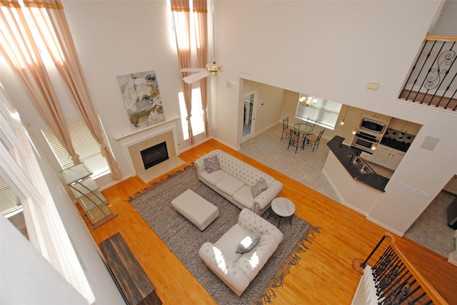 living room with hardwood / wood-style floors, ceiling fan with notable chandelier, and a high ceiling