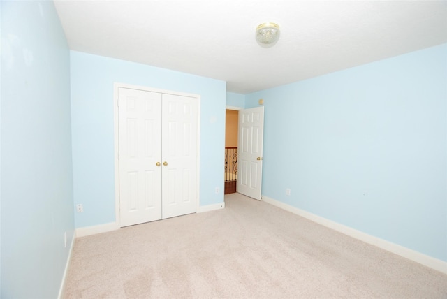 unfurnished bedroom featuring light carpet and a closet