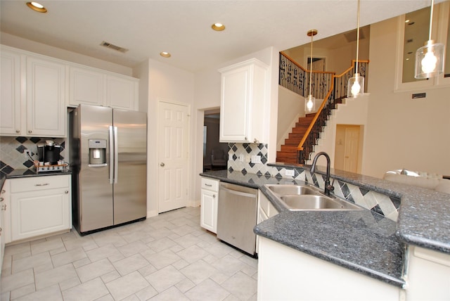 kitchen featuring backsplash, sink, appliances with stainless steel finishes, decorative light fixtures, and white cabinetry