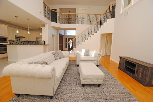 living room featuring a towering ceiling and light hardwood / wood-style flooring