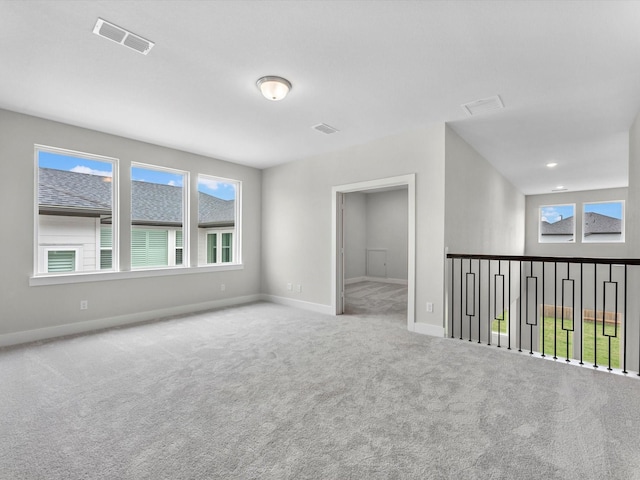 spare room with a healthy amount of sunlight, baseboards, carpet flooring, and visible vents