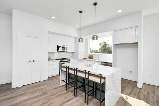 kitchen featuring appliances with stainless steel finishes, decorative light fixtures, white cabinetry, and a kitchen island