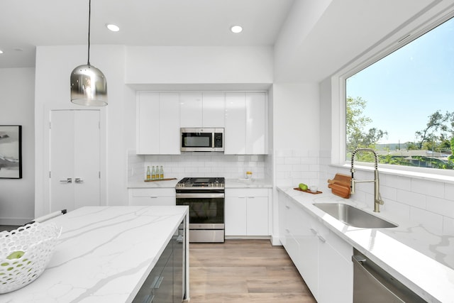 kitchen featuring pendant lighting, white cabinets, sink, appliances with stainless steel finishes, and tasteful backsplash