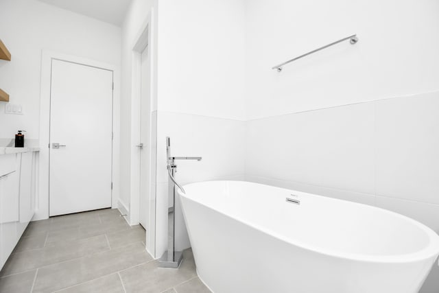 bathroom with a tub to relax in, tile patterned flooring, and vanity