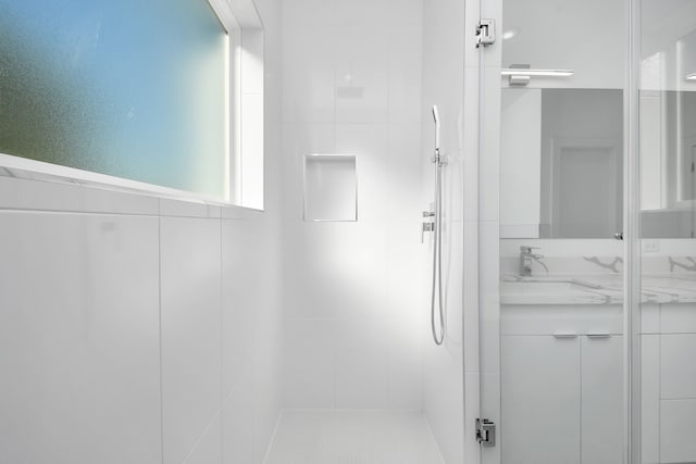 bathroom featuring a shower with door and vanity