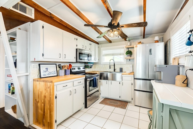 kitchen featuring light tile patterned floors, white cabinetry, ceiling fan, stainless steel appliances, and sink