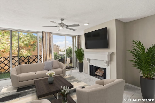 living room with ceiling fan, a fireplace, and a textured ceiling