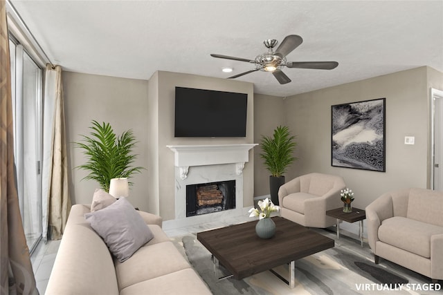 living room featuring ceiling fan, a fireplace, a textured ceiling, and light hardwood / wood-style flooring