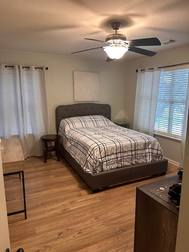 bedroom featuring a textured ceiling, light hardwood / wood-style flooring, and ceiling fan