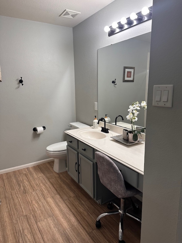 bathroom with hardwood / wood-style flooring, vanity, and toilet