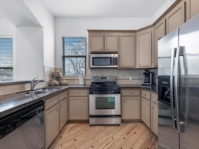 kitchen featuring a healthy amount of sunlight, sink, stainless steel appliances, and light wood-type flooring