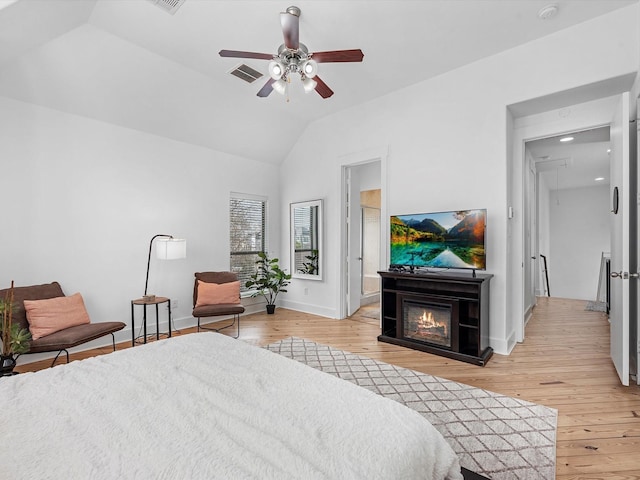 bedroom with ensuite bath, ceiling fan, light hardwood / wood-style floors, and vaulted ceiling