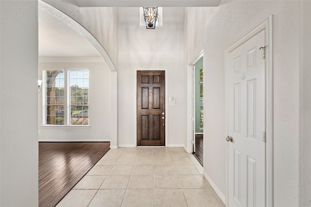 foyer entrance featuring a chandelier, crown molding, and light hardwood / wood-style flooring