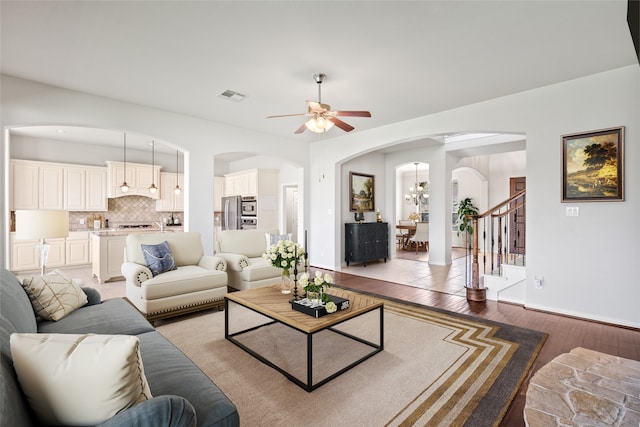 living room with ceiling fan with notable chandelier and hardwood / wood-style flooring