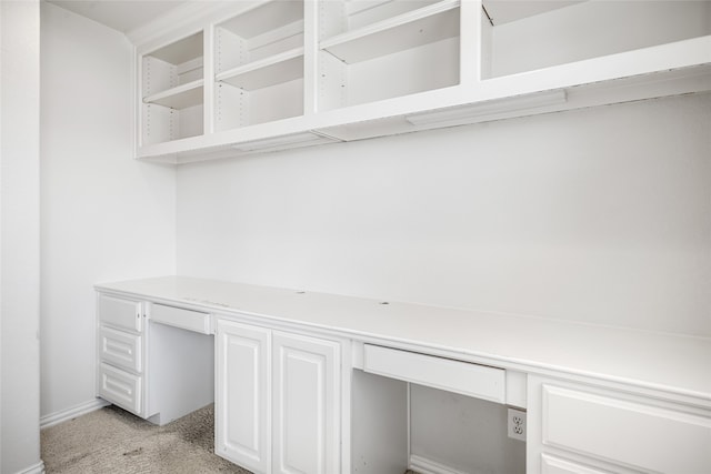 unfurnished office featuring light colored carpet and built in desk