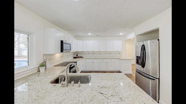 kitchen with light stone counters, sink, and appliances with stainless steel finishes