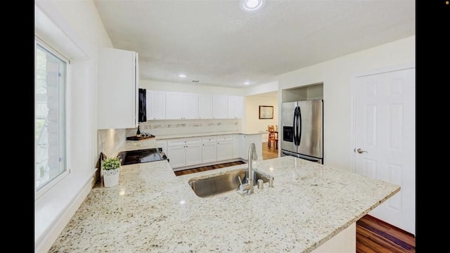 kitchen featuring light stone counters, sink, dark wood-type flooring, and stainless steel refrigerator with ice dispenser