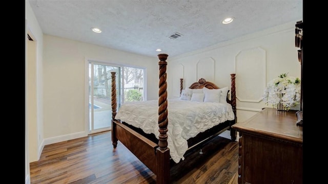 bedroom with access to exterior, dark hardwood / wood-style flooring, and a textured ceiling