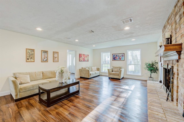 living room featuring a large fireplace, hardwood / wood-style floors, and a textured ceiling