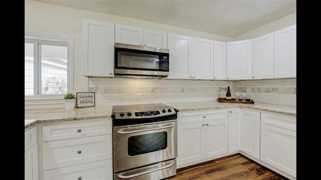 kitchen featuring dark wood-type flooring, light stone counters, decorative backsplash, white cabinets, and appliances with stainless steel finishes