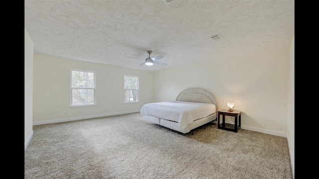 bedroom with a textured ceiling, light colored carpet, and ceiling fan