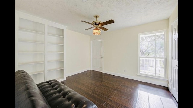 unfurnished living room featuring dark hardwood / wood-style floors, ceiling fan, and a textured ceiling