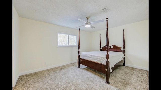 bedroom with ceiling fan, light colored carpet, and a textured ceiling