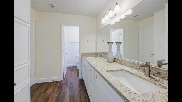 bathroom featuring an inviting chandelier, hardwood / wood-style floors, a textured ceiling, toilet, and vanity