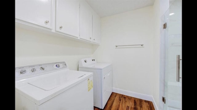 washroom featuring cabinets, dark wood-type flooring, and washing machine and clothes dryer