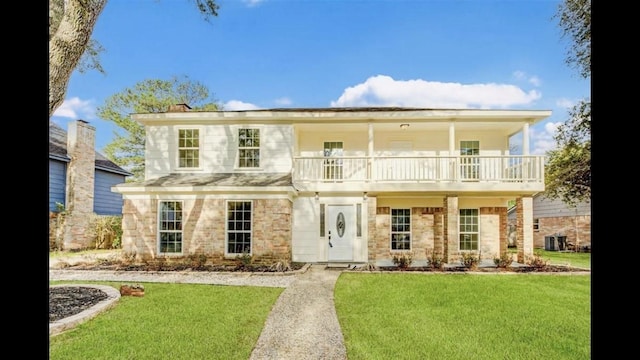 view of front of property featuring central AC, a balcony, and a front lawn