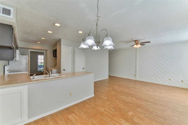 kitchen featuring light hardwood / wood-style flooring, decorative light fixtures, a textured ceiling, and sink